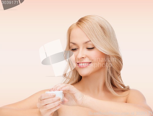 Image of beautiful woman applying cream