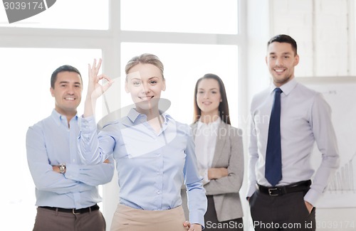 Image of smiling businesswoman showing ok-sign in office