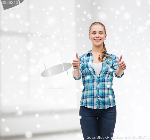 Image of smiling girl showing thumbs up over white room