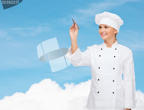Image of smiling female chef writing something on air