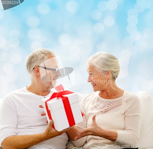 Image of happy senior couple with gift box at home