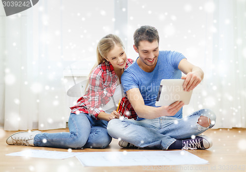 Image of smiling couple with tablet and blueprint at home