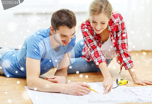 Image of smiling couple with  blueprint at home