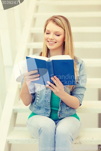 Image of smiling teenage girl reading book