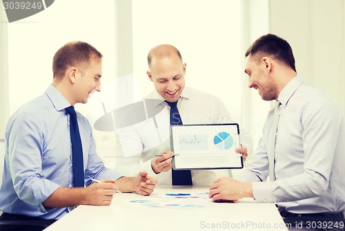 Image of smiling businessmen with papers in office