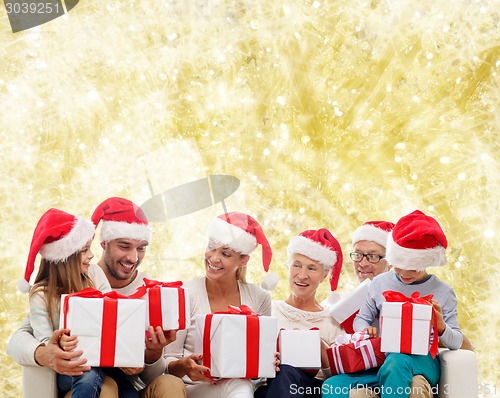 Image of happy family in santa helper hats with gift boxes