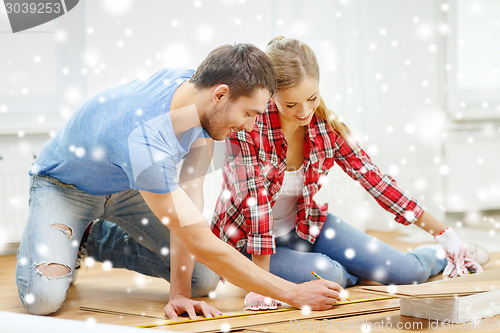 Image of smiling couple measuring wood flooring