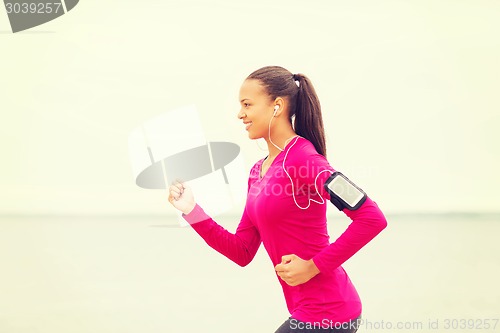 Image of smiling young woman running outdoors