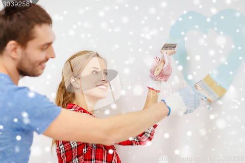 Image of smiling couple painting small heart on wall