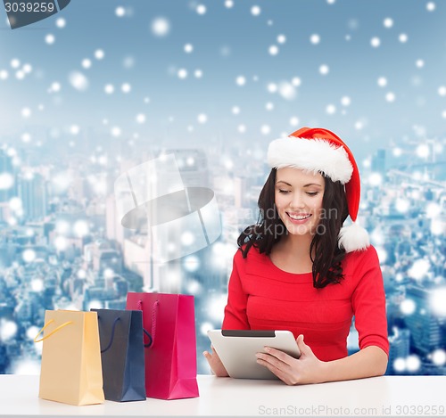 Image of smiling woman with shopping bags and tablet pc