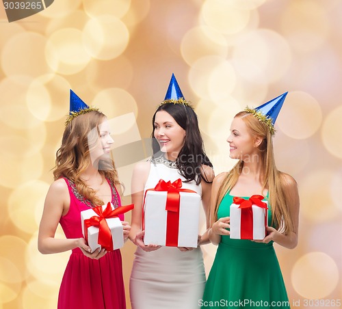 Image of smiling women in party caps with gift boxes