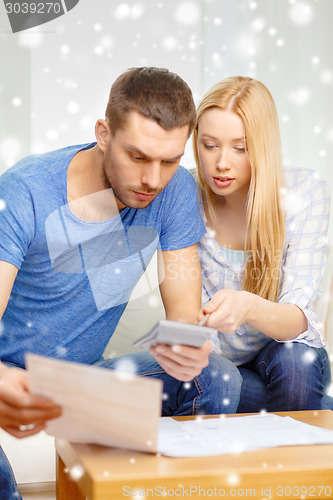 Image of busy couple with papers and calculator at home