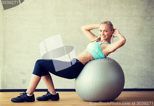 Image of smiling woman with exercise ball in gym