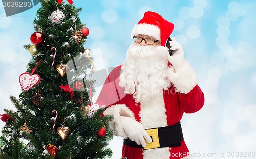 Image of santa claus with smartphone and christmas tree