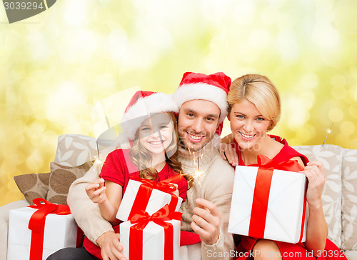 Image of smiling family holding gift boxes and sparkles