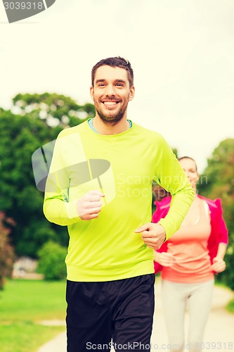 Image of smiling couple running outdoors