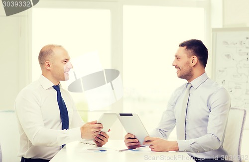 Image of two smiling businessmen with tablet pc in office