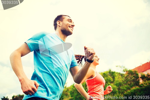 Image of smiling couple running outdoors