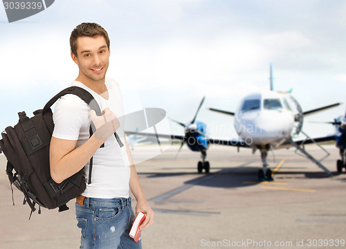 Image of smiling student with backpack and book at airport