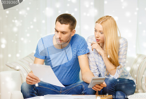 Image of busy couple with papers and calculator at home