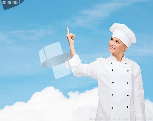 Image of smiling female chef pointing finger to something