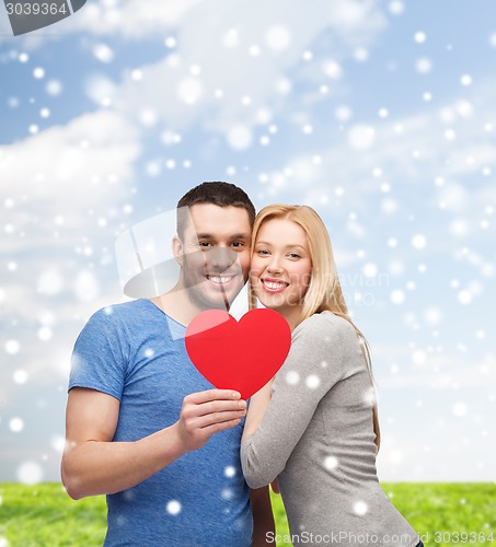 Image of happy couple with red heart shape hugging outdoors