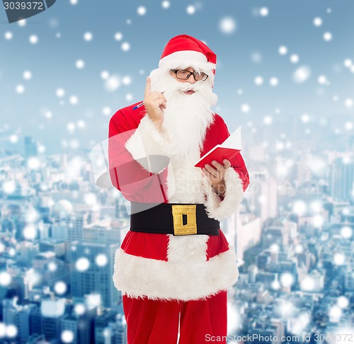 Image of man in costume of santa claus with notepad