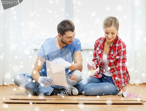 Image of smiling couple measuring wood flooring