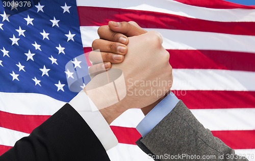 Image of close up of hands arm wrestling over american flag