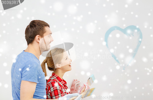 Image of smiling couple painting small heart on wall