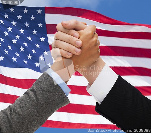 Image of close up of hands armwrestling over american flag