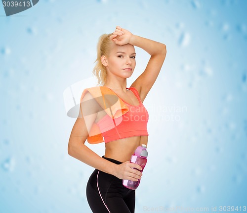 Image of tired sporty woman with towel and water bottle