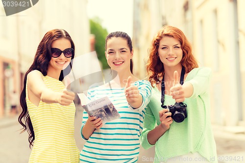 Image of smiling teenage girls with city guide and camera