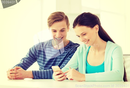 Image of two smiling students with smartphone at school