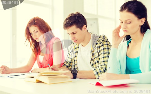 Image of tired students with textbooks and books at school