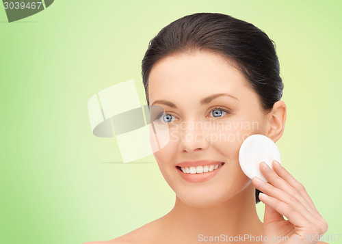 Image of smiling woman cleaning face skin with cotton pad