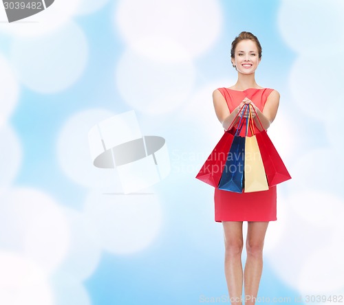 Image of smiling elegant woman in dress with shopping bags
