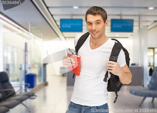 Image of smiling student with backpack and book at airport