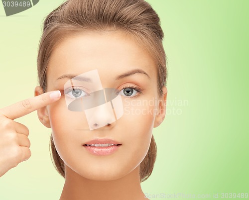 Image of beautiful young woman pointing finger to her eye