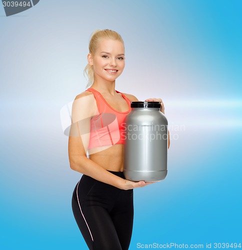 Image of smiling sporty woman with jar of protein