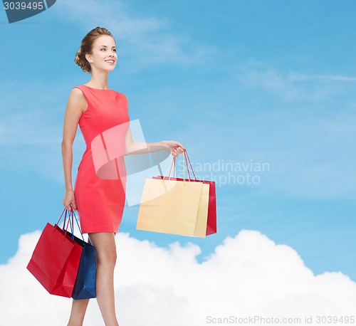 Image of smiling elegant woman in dress with shopping bags