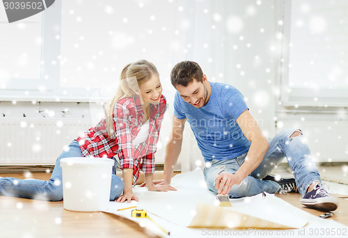 Image of smiling couple smearing wallpaper with glue