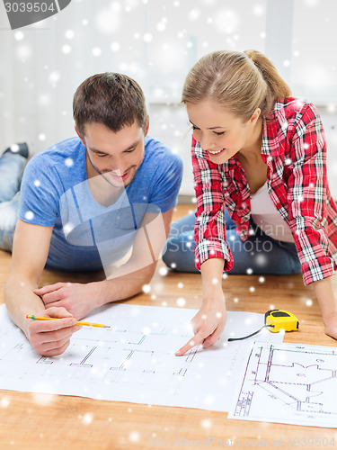 Image of smiling couple with blueprint at home