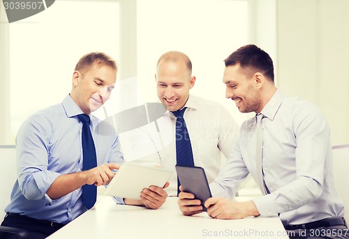 Image of three smiling businessmen with tablet pc in office