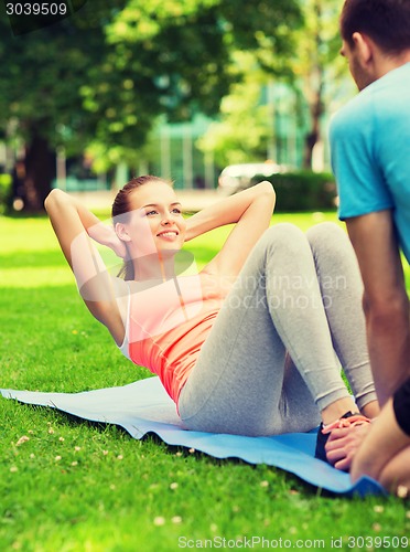 Image of smiling woman doing exercises on mat outdoors