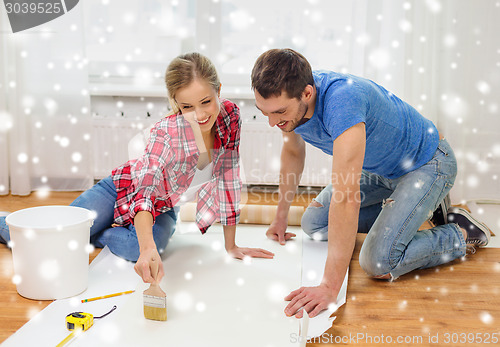 Image of smiling couple smearing wallpaper with glue