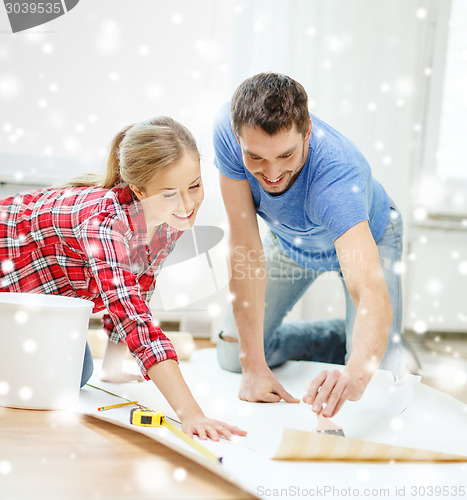 Image of smiling couple smearing wallpaper with glue