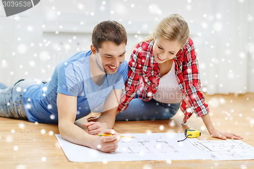 Image of smiling couple with blueprint at home