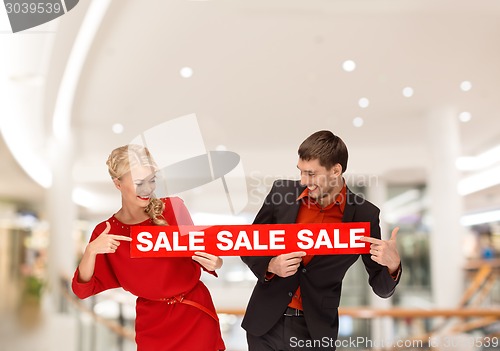 Image of happy young couple with red shopping bags in mall