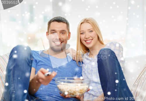 Image of smiling couple watching tv at home